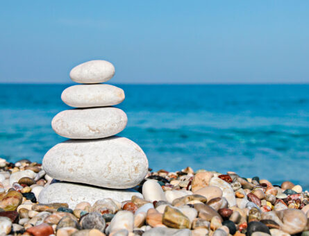 Zen stones stacked at beach against a blue sky and sea with copy space